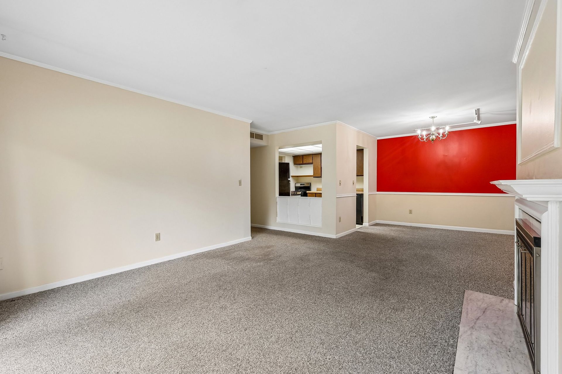 Photo of a living room with a fireplace and dining area and kitchen in the background