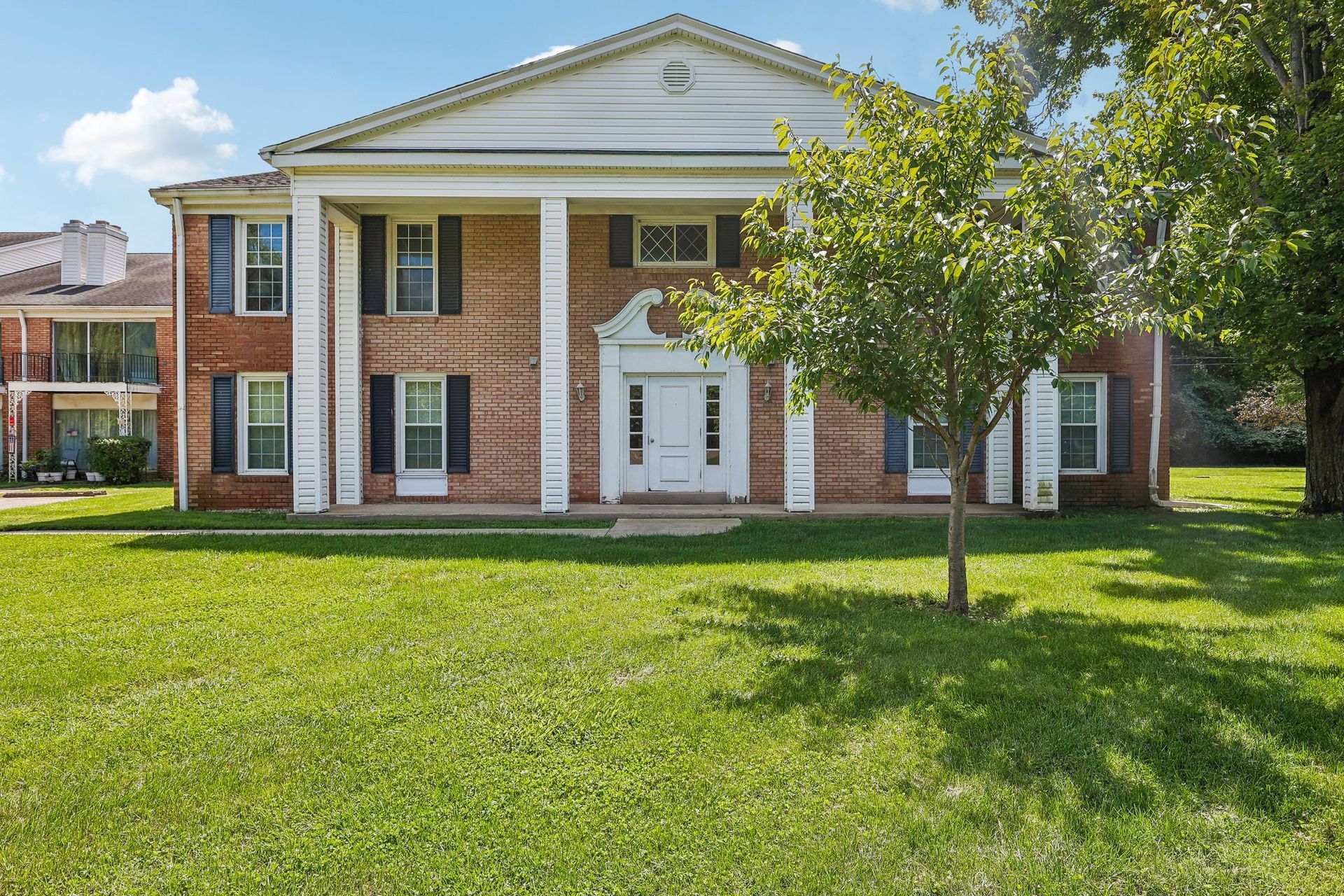 Photo of an apartment building entrance with a tree out front