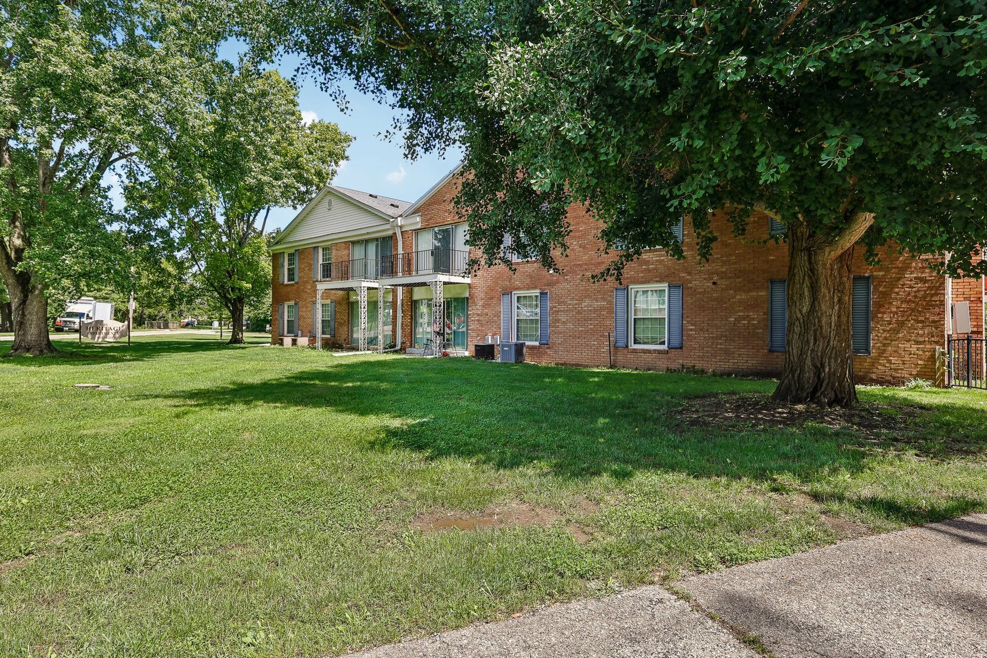 Photo of an apartment building with a lawn and a few trees in front of it