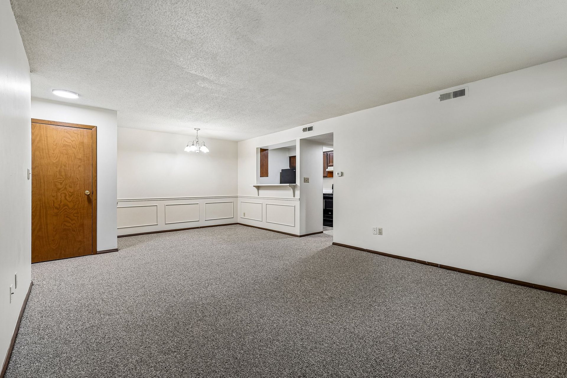 Photo of a living room with the dining area and kitchen in the background