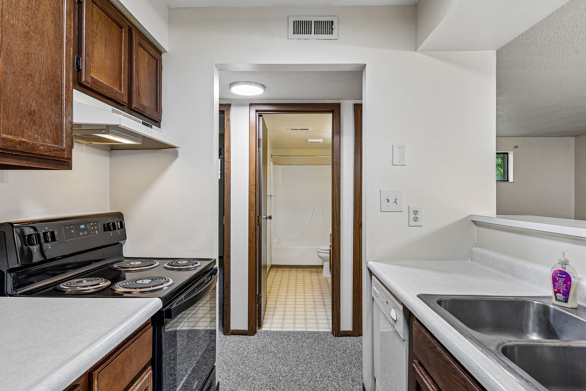 Photo of a kitchen with a bathroom door in the background