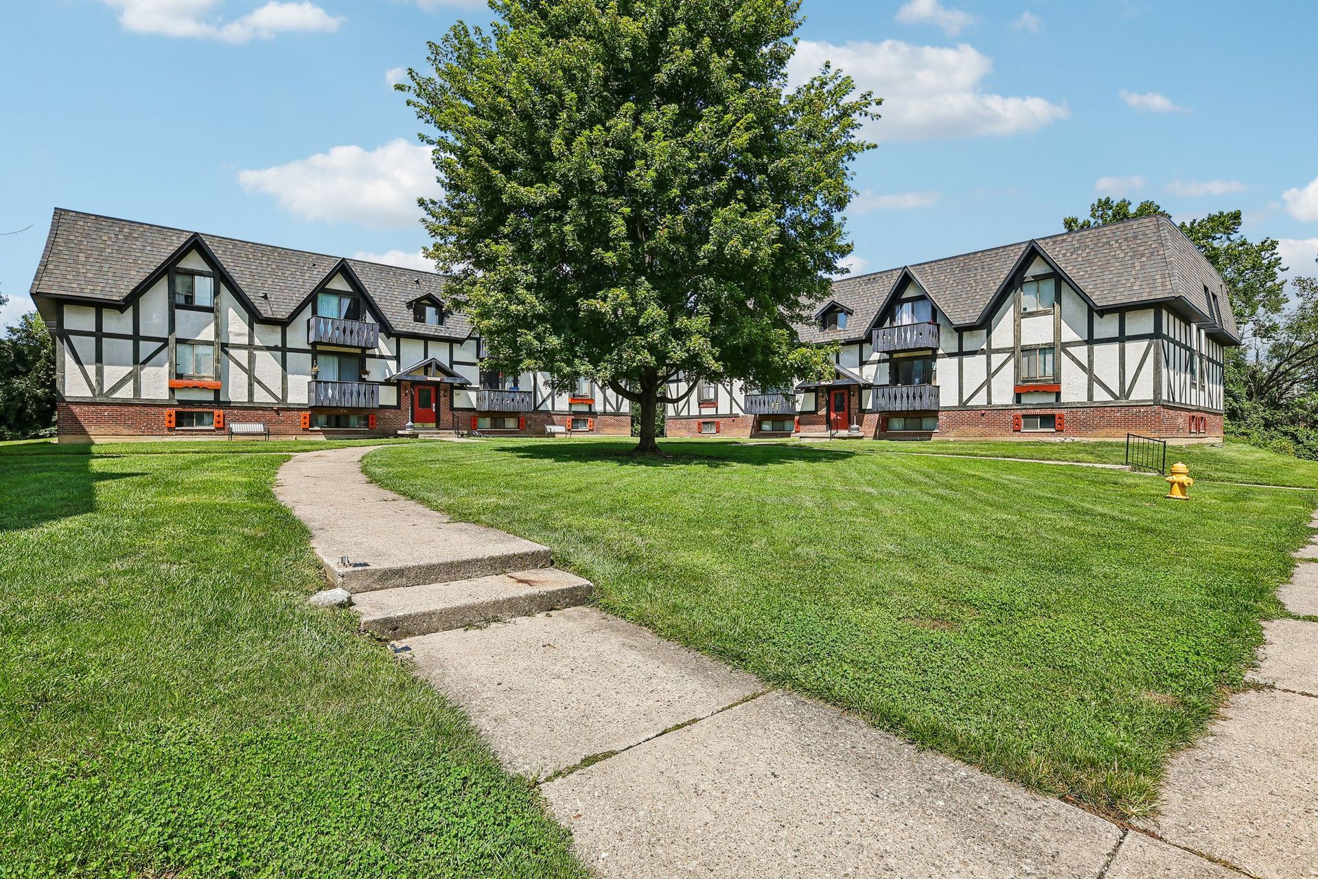 Photo of a an L-Shaped apartment building with a yard in front
