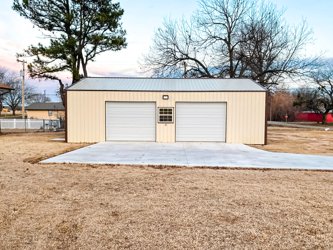 A metal garage with an attached porch. Gray and black siding with a white garage door.
