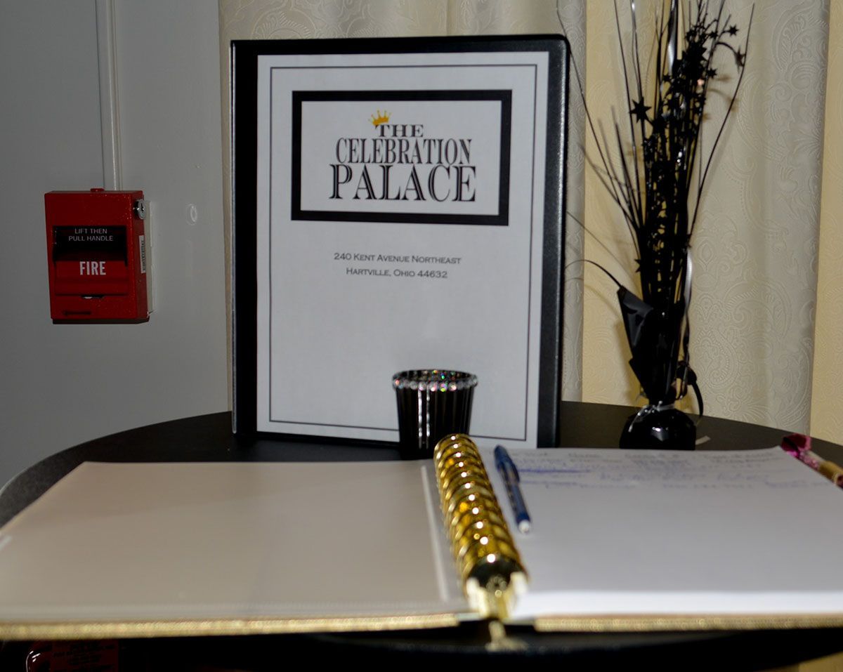 Hotel lobby sign for The Celebration Palace behind a gold pen on a reception desk