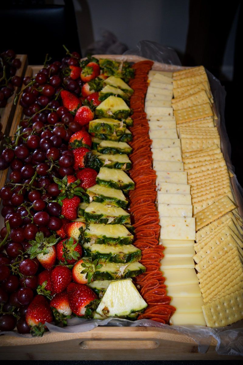 Tray of assorted fresh fruits and crackers arranged in neat rows for a buffet platter