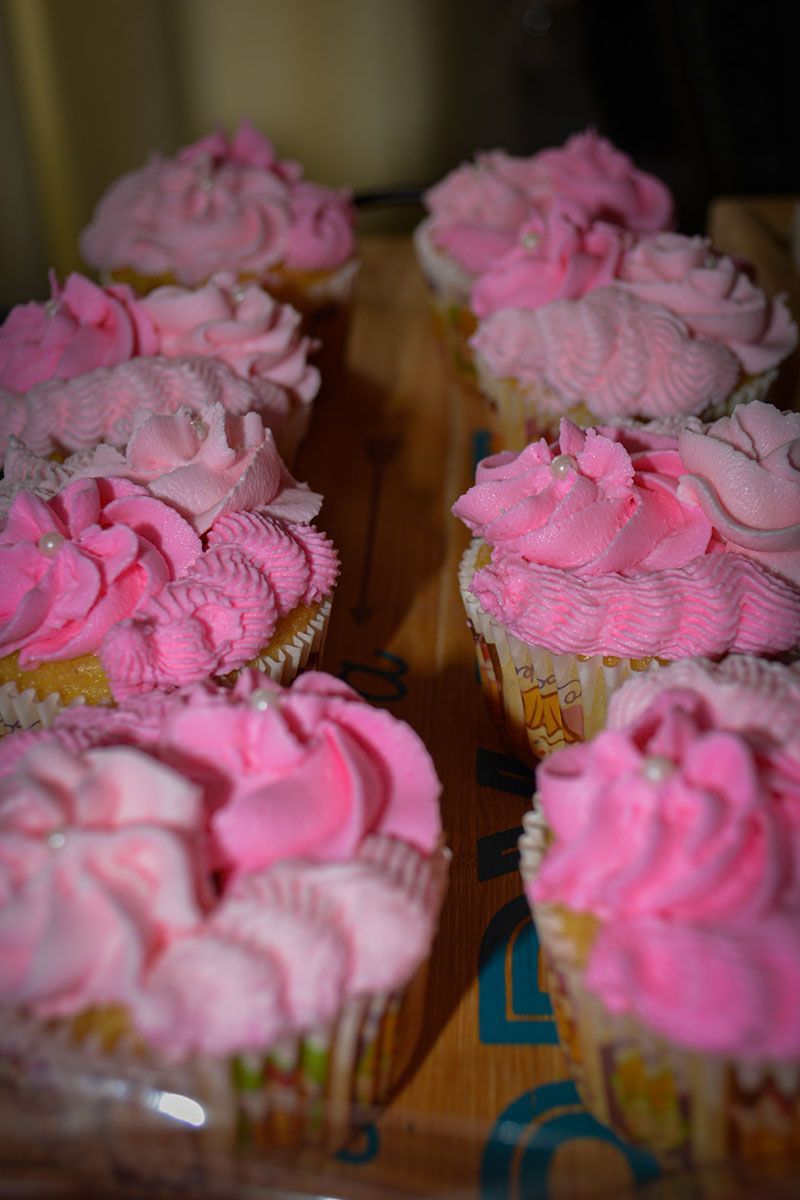 Pink frosted cupcakes arranged in rows on a tray