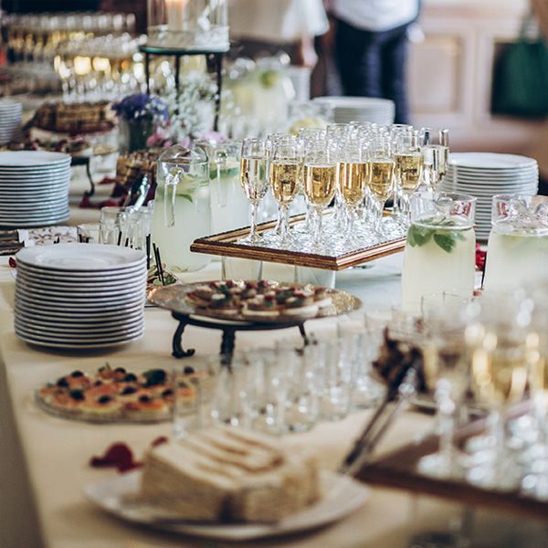 Buffet table with champagne flutes, appetizers, plates, and pitchers in a bright event setting