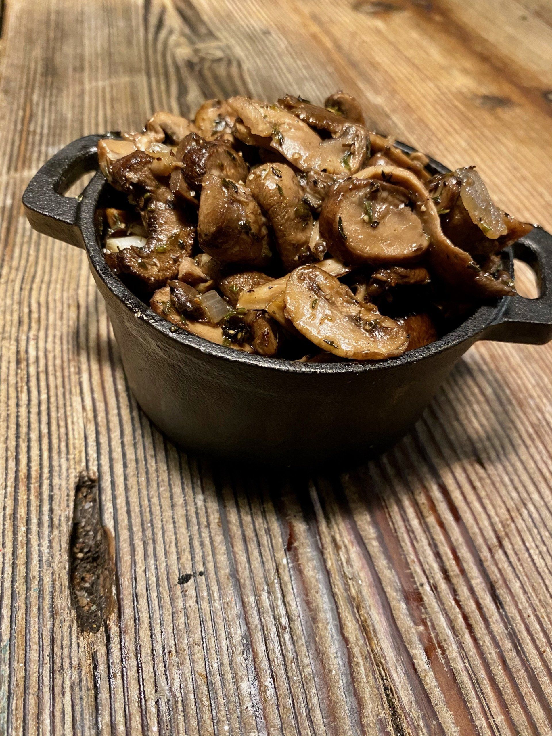 a bowl of mushrooms sits on a wooden table