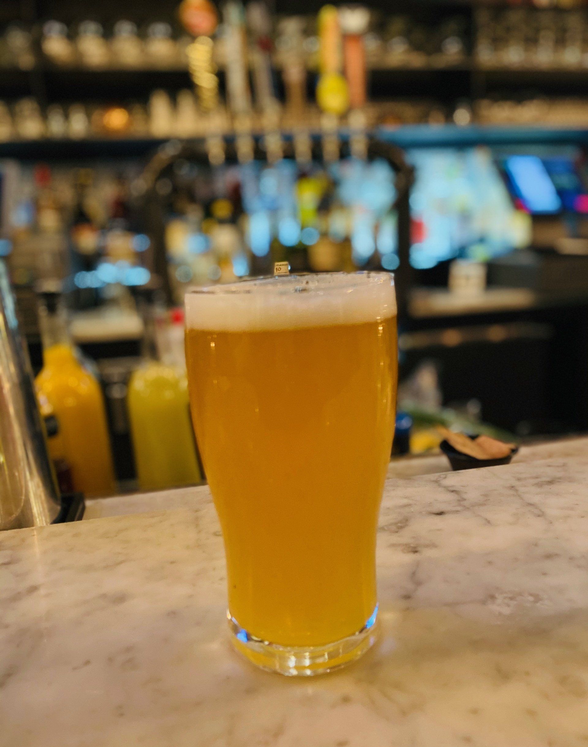 a glass of beer sits on a counter in front of a bar