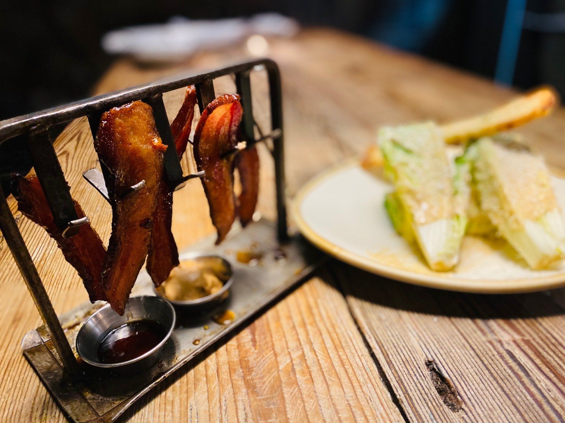a plate of food on a wooden table including bacon and avocado