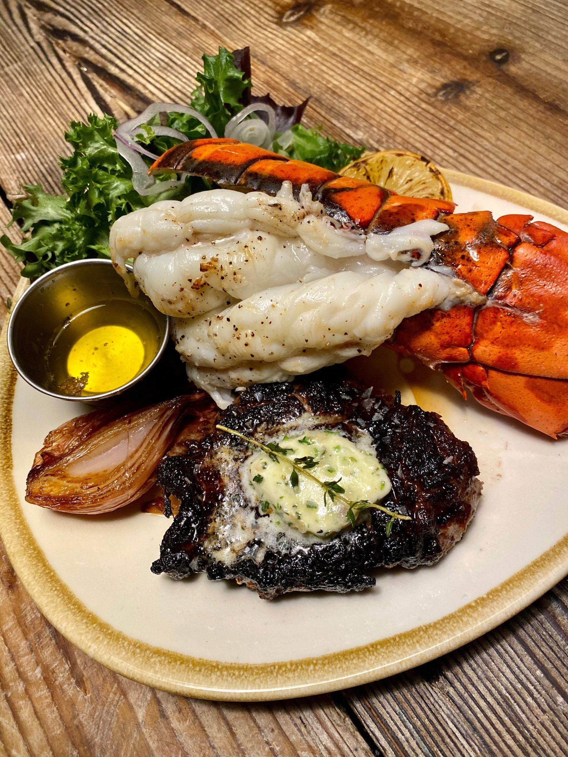 a plate of food with a steak and lobster on it