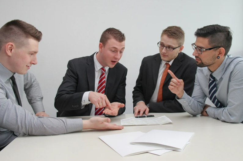 Un grupo de hombres de negocios están sentados alrededor de una mesa teniendo una reunión.