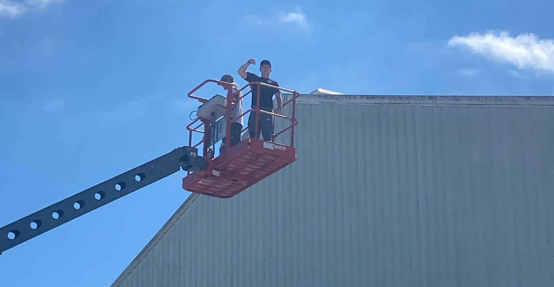 Picture of Patrick on a lift painting a large storage tank.
