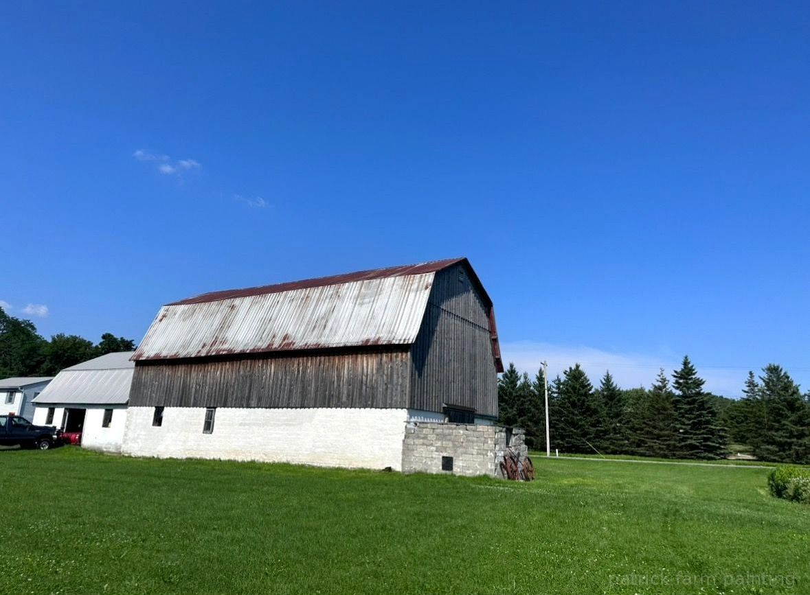 Barn painting services by Patrick Farm Painting in Norwich, New York. This image features a restored rural barn or farmhouse surrounded by open countryside, green grass, and natural outdoor lighting. The freshly painted exterior highlights the detailed craftsmanship of experienced barn painters and the trusted farm painting guy from Patrick Farm Painting, a company that paints barns in New York. The siding, trim, and exterior surfaces appear clean, vibrant, and professionally coated, creating a vivid before-and-after transformation. This detailed description helps visually impaired website visitors imagine the peaceful farm setting, the scale of the building, and the quality of the completed farm painting project.