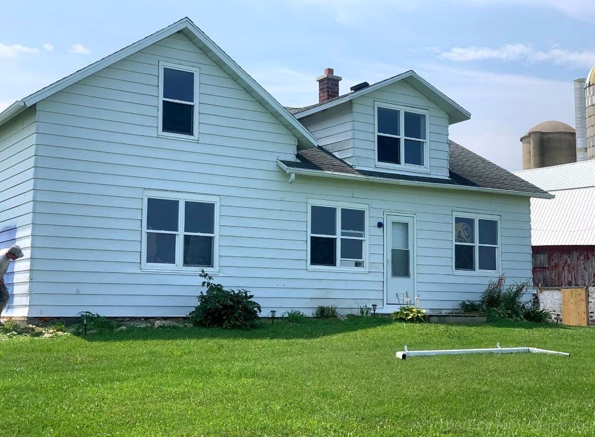 Barn painting services by Patrick Farm Painting in Norwich, New York. This image features a restored rural barn or farmhouse surrounded by open countryside, green grass, and natural outdoor lighting. The freshly painted exterior highlights the detailed craftsmanship of experienced barn painters and the trusted farm painting guy from Patrick Farm Painting, a company that paints barns in New York. The siding, trim, and exterior surfaces appear clean, vibrant, and professionally coated, creating a vivid before-and-after transformation. This detailed description helps visually impaired website visitors imagine the peaceful farm setting, the scale of the building, and the quality of the completed farm painting project.