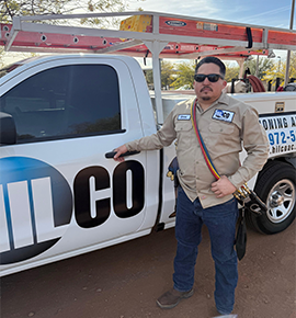 Man in work attire standing by a white work truck with 