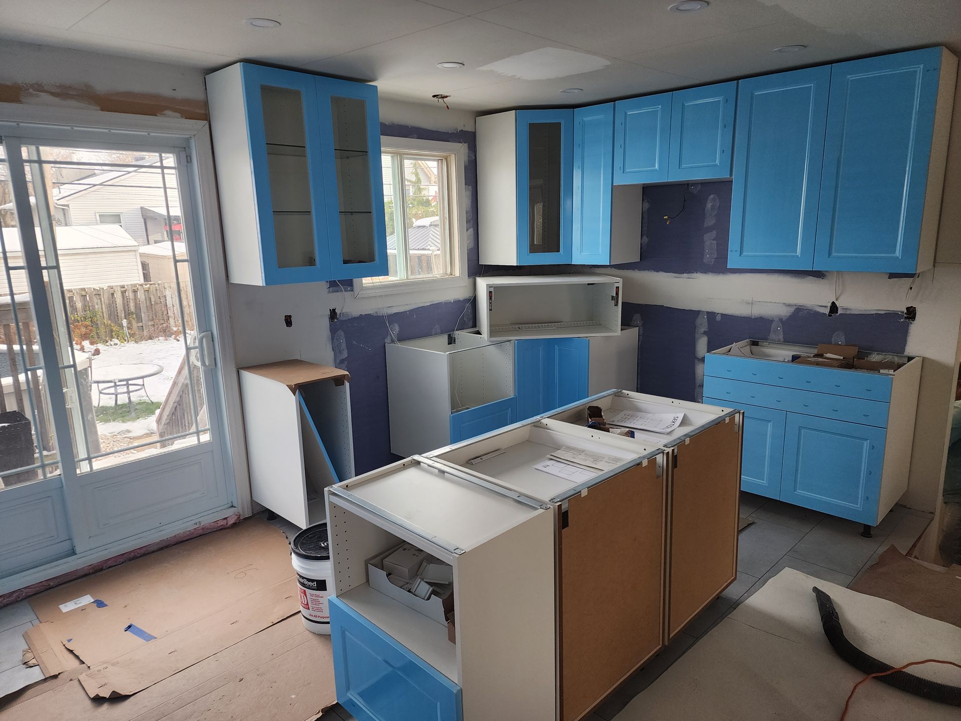 A kitchen is being remodeled with blue cabinets and white cabinets.