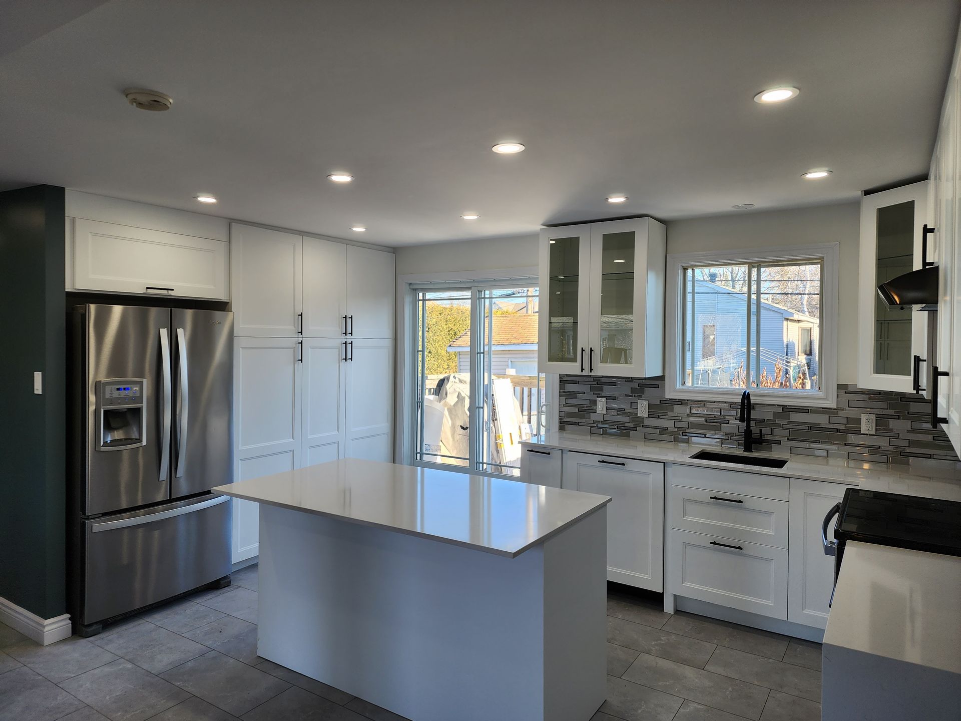 A kitchen with white cabinets , stainless steel appliances , and a large island.