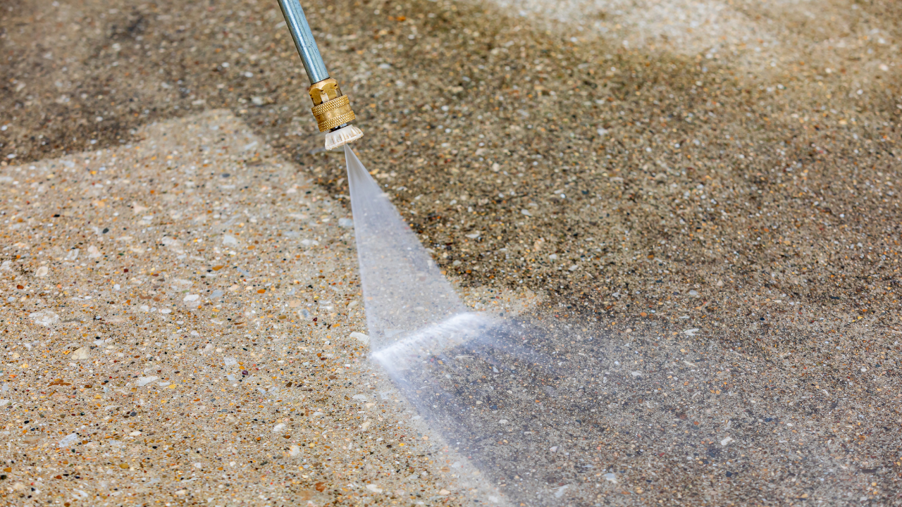 Water spraying from a hose nozzle onto a sandy surface