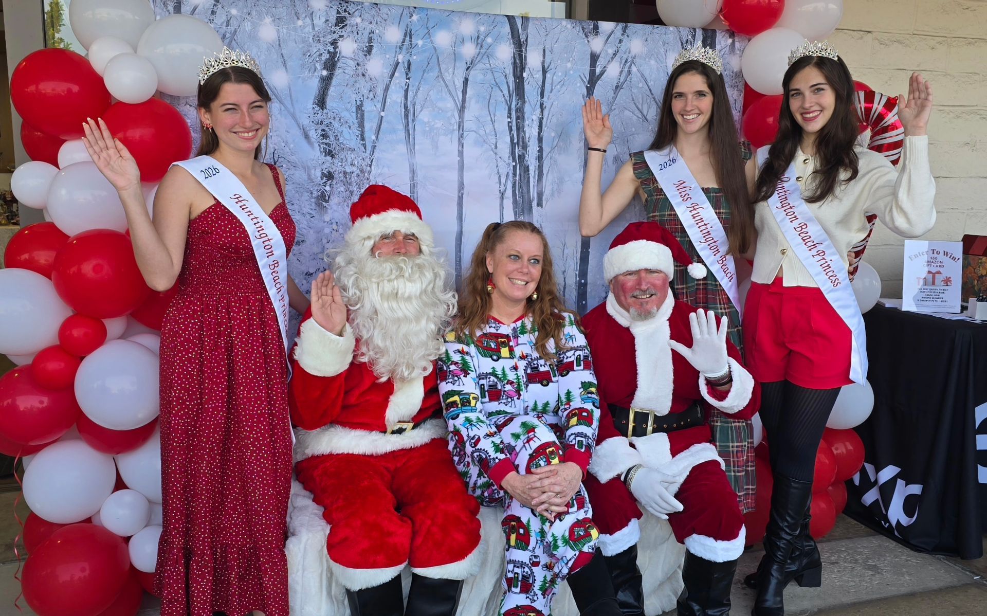 Miss HB and her court People with Santa and crowns pose in front of a winter-themed backdrop with balloons.