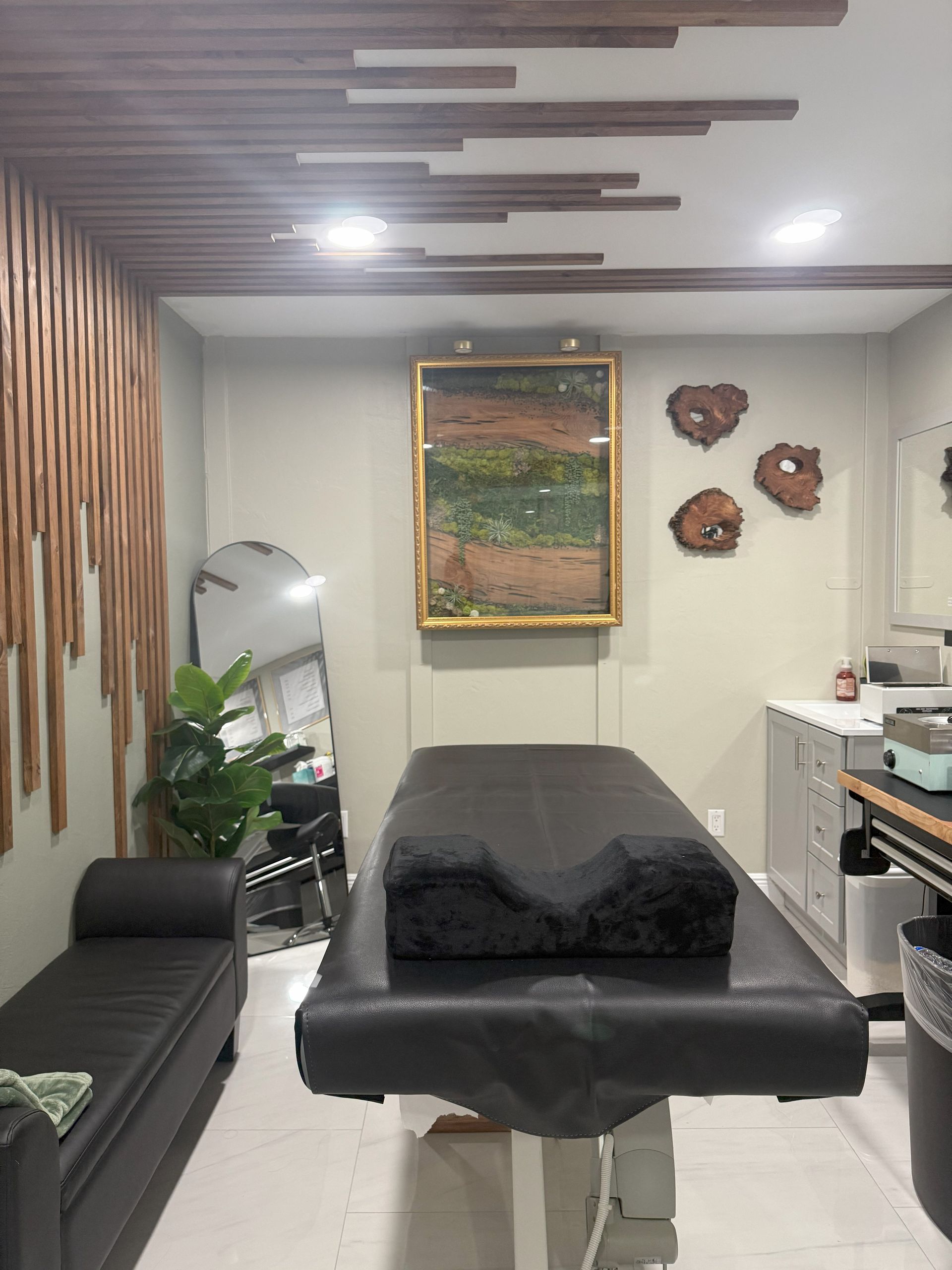 Salon interior with massage table, artwork, and wooden wall accents.