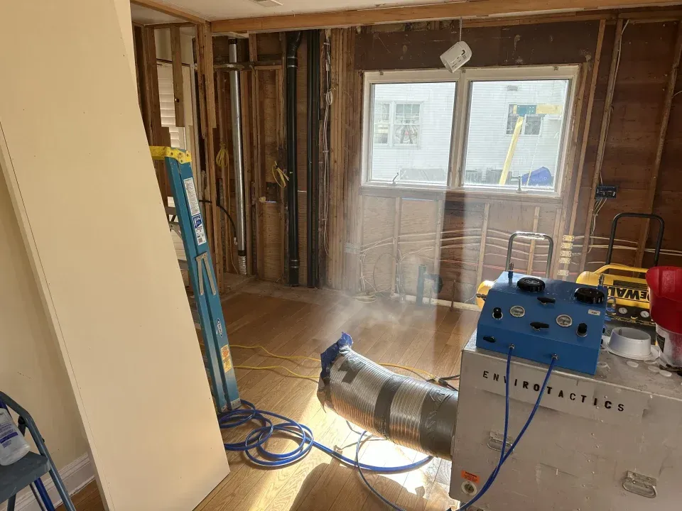 Damp, stained basement corner with peeling white walls and a dirty concrete floor