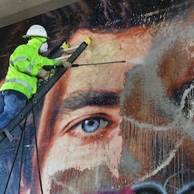 image of an art conservator cleaning off a Kent Twitchell mural 