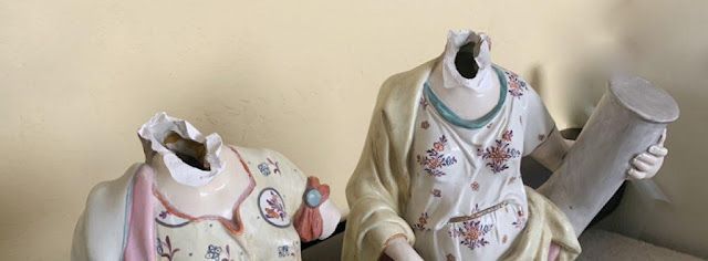 two chinese figural statues with their heads broken off 