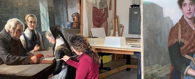 a white woman with wavy hair sits in front of a large painting while using a cotton swab to clean its surface