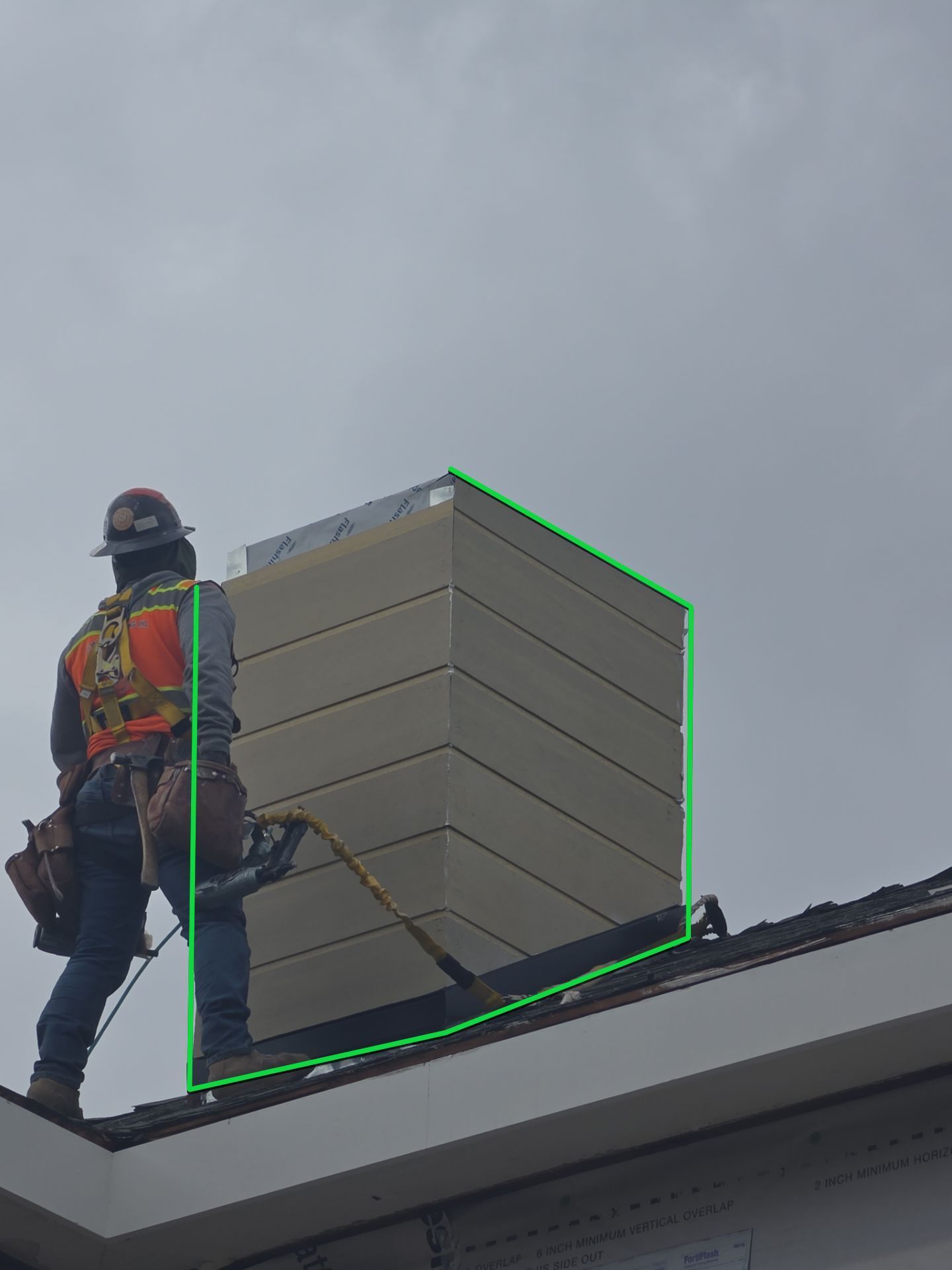 Worker on a rooftop beside a large stack of beige vents or HVAC units.