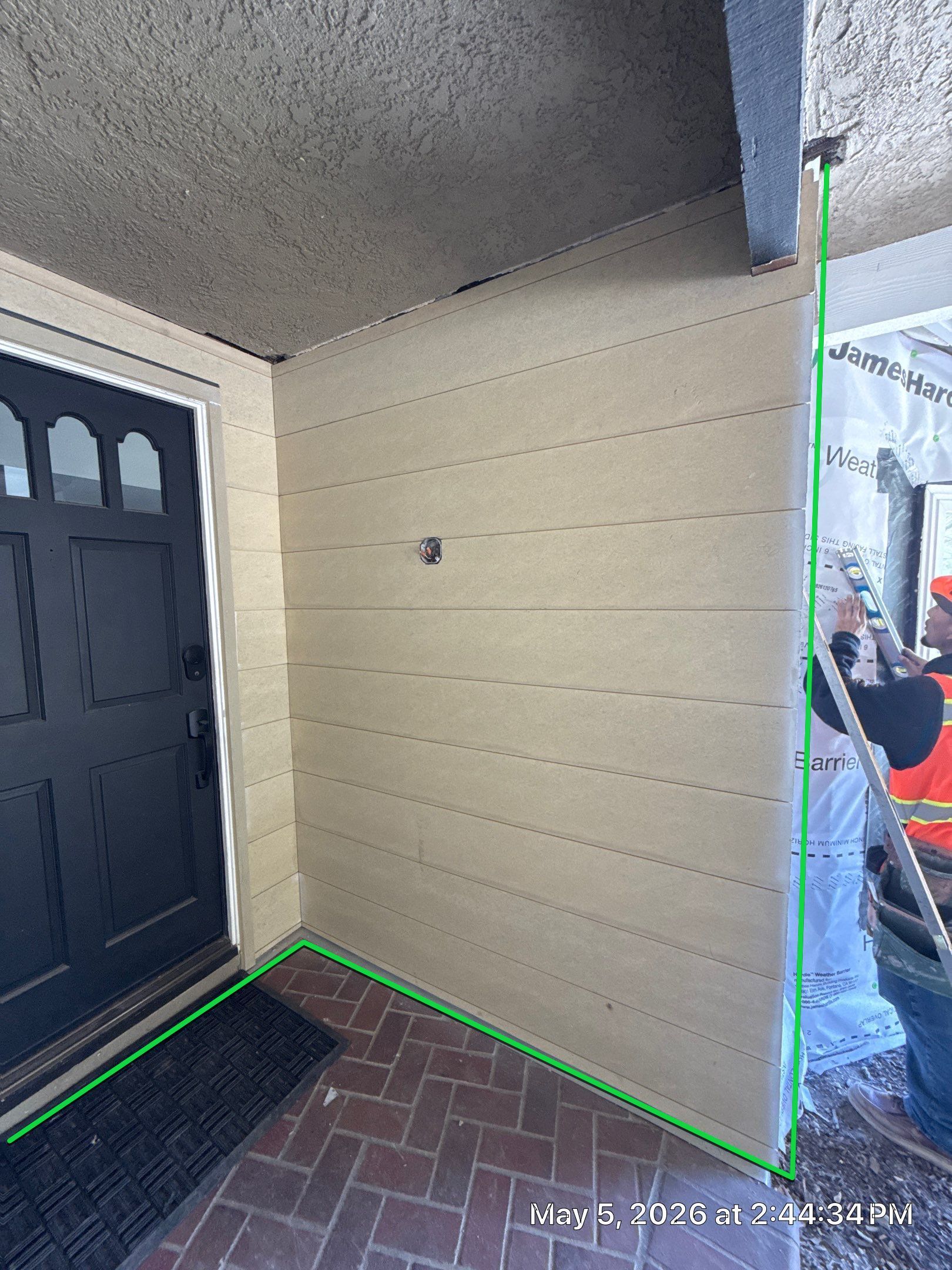 Front porch entryway with black door, cream wall, and visible measuring lines on the floor and wall.