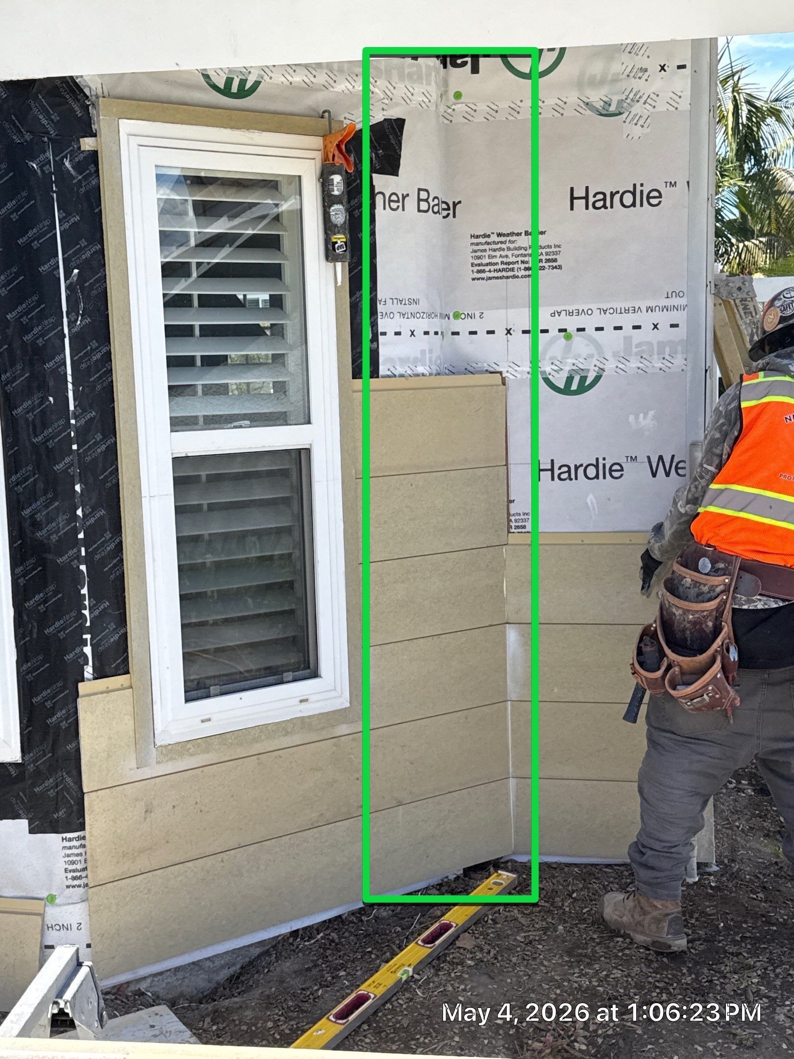 Construction worker measuring wall beside a window on an unfinished exterior wall