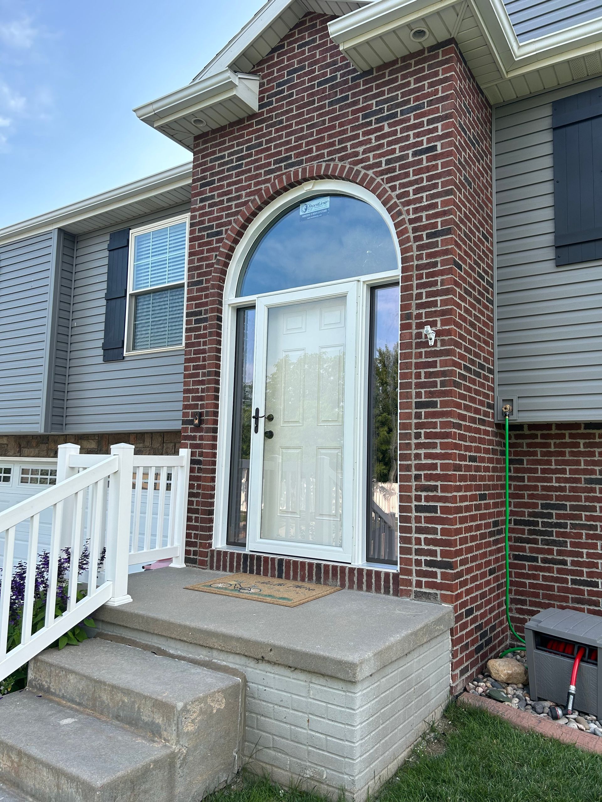 A brick house with a white door and a white fence.