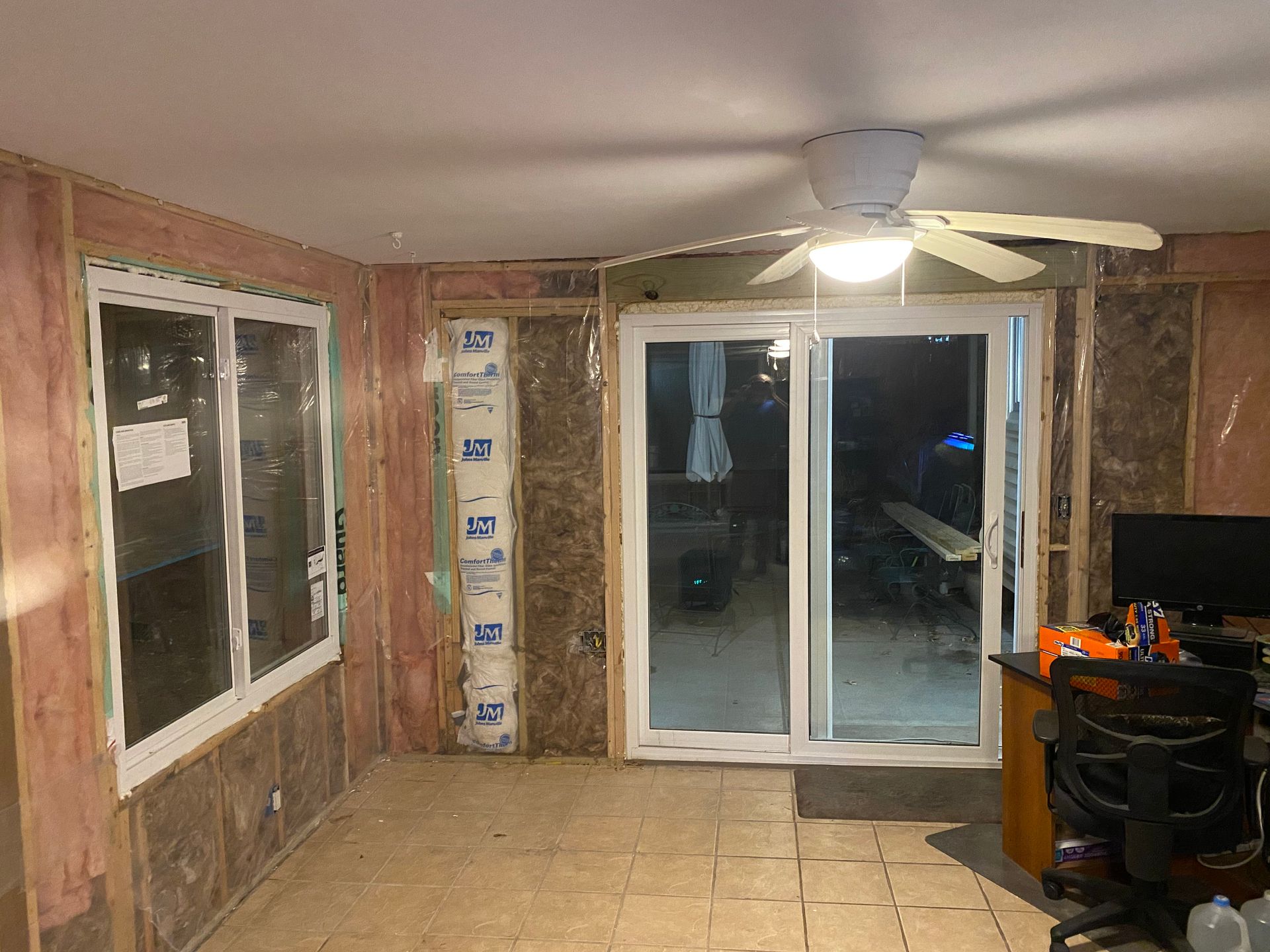 A room with a ceiling fan and a sliding glass door.