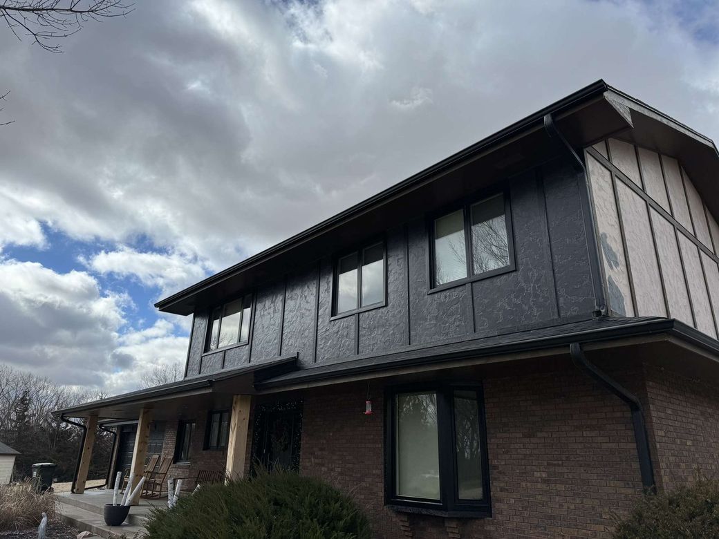 A large house with a lot of windows and a cloudy sky in the background.
