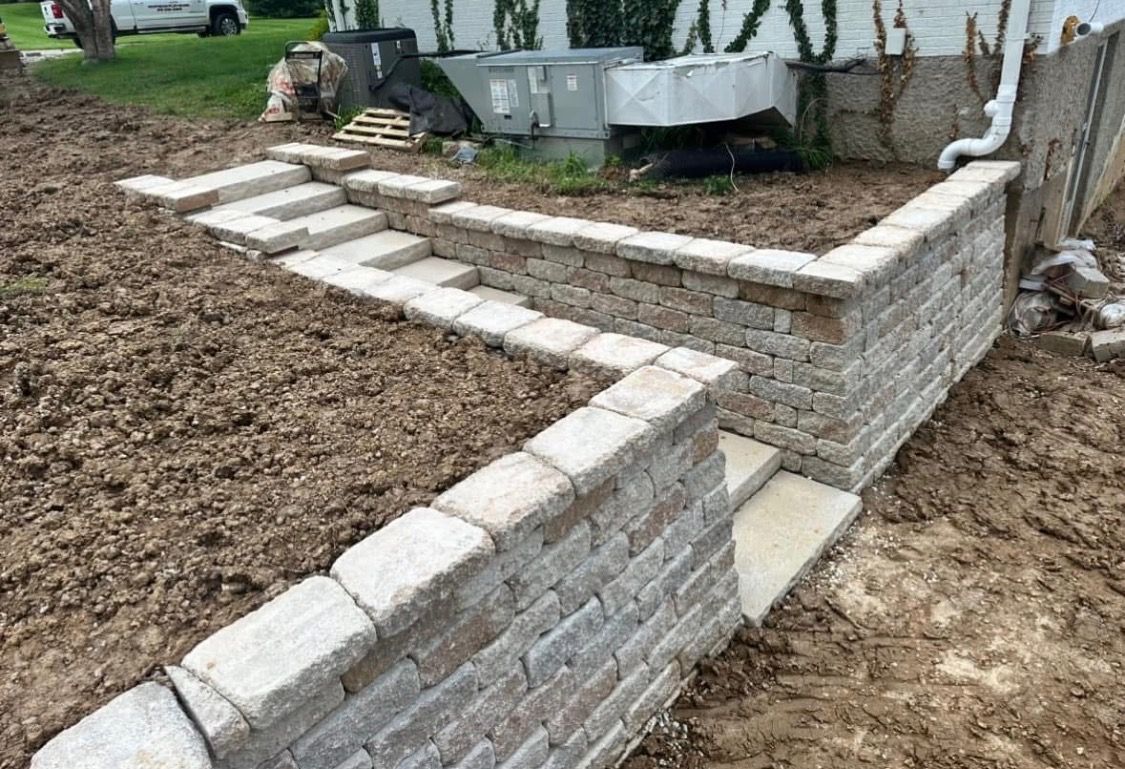 Curved white brick garden wall with stepping stones beside a house and yard【】
