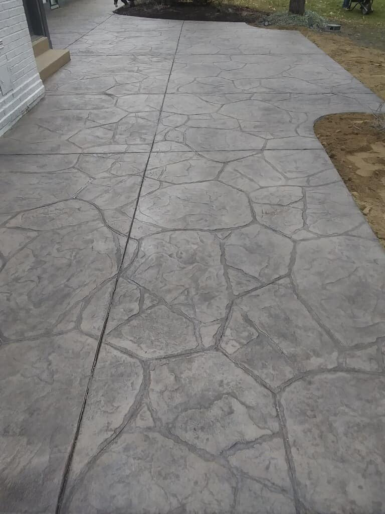 Cracked concrete walkway beside a house and grassy yard
