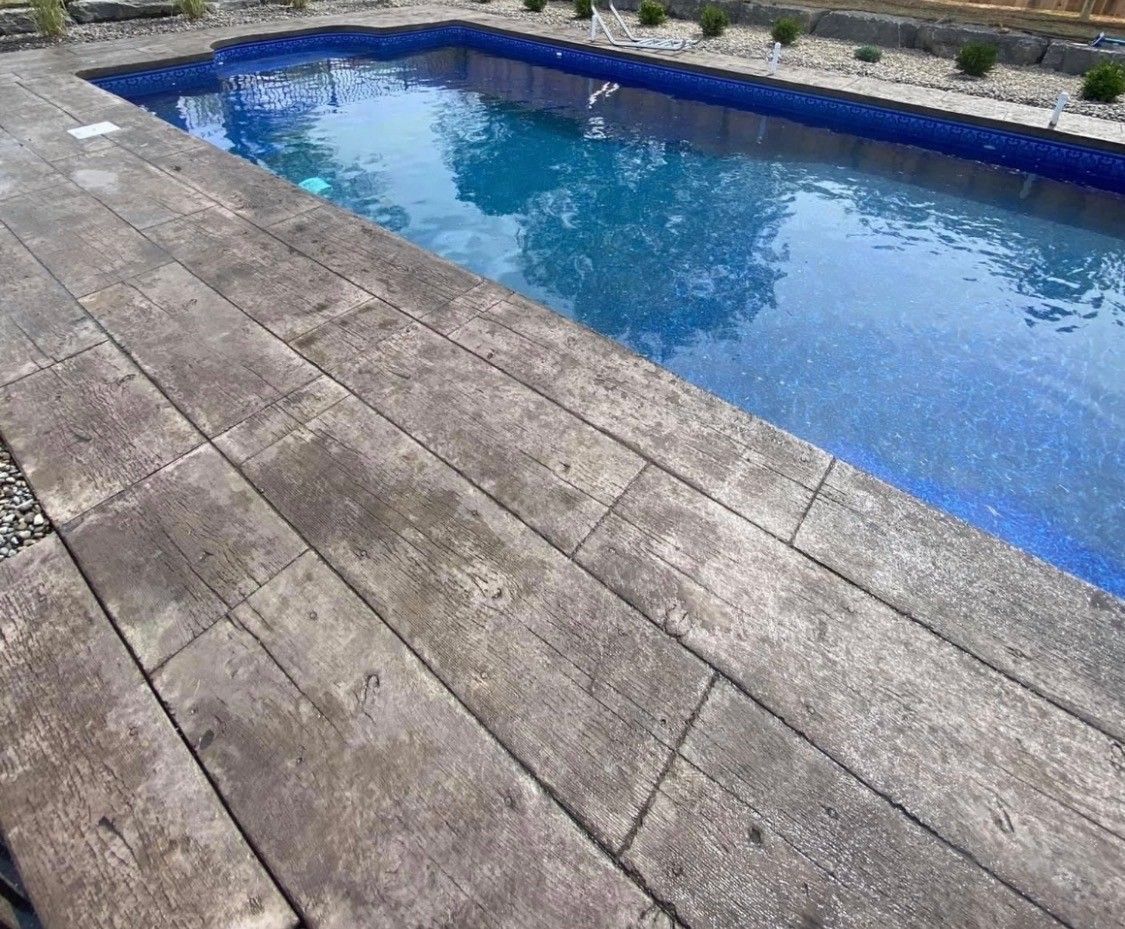 Blue swimming pool beside a weathered wooden deck and stone patio