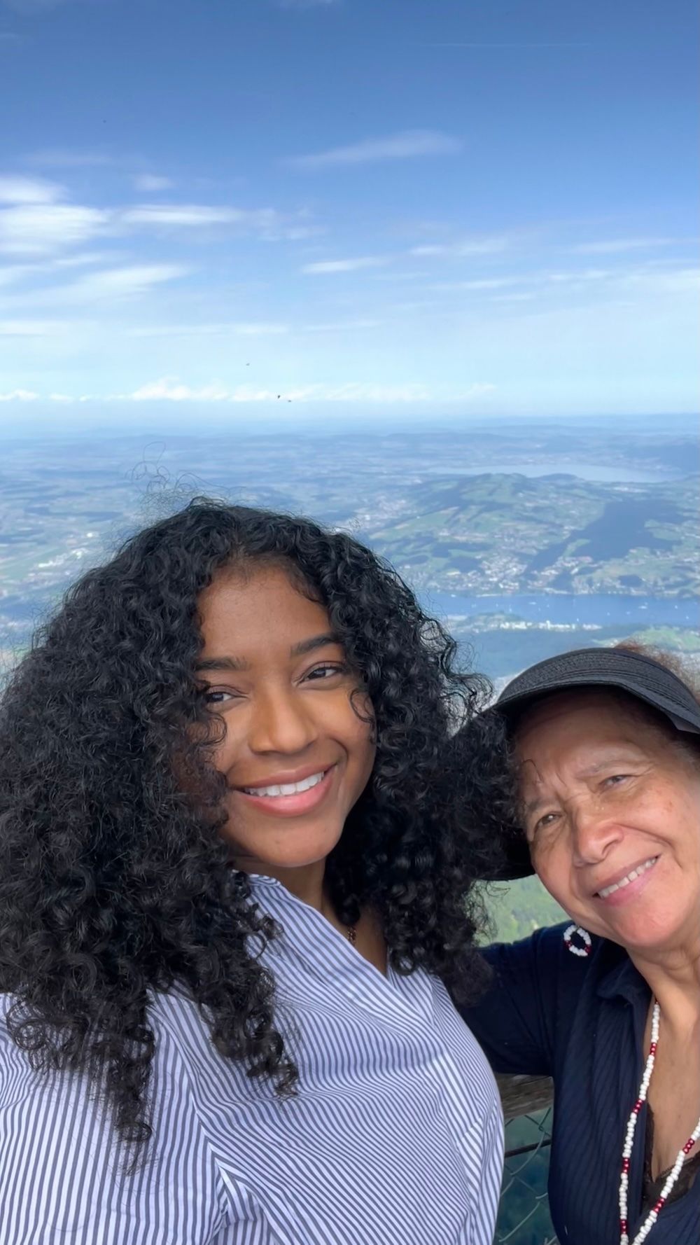 Jess and her grandmother smile for a selfie on Mt. Pilatus with a sweeping view of Lake Lucerne and the surrounding landscape behind them. The mountaintop photo shows another reason Switzerland is worth visiting for scenic viewpoints and meaningful family memories.
