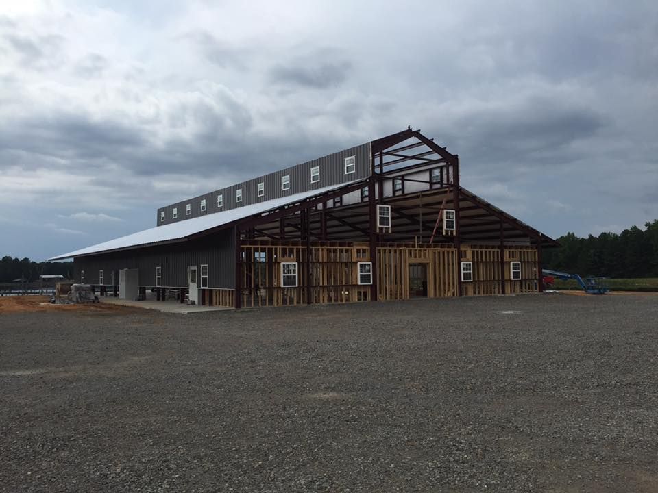 A large building is being built in a gravel lot.