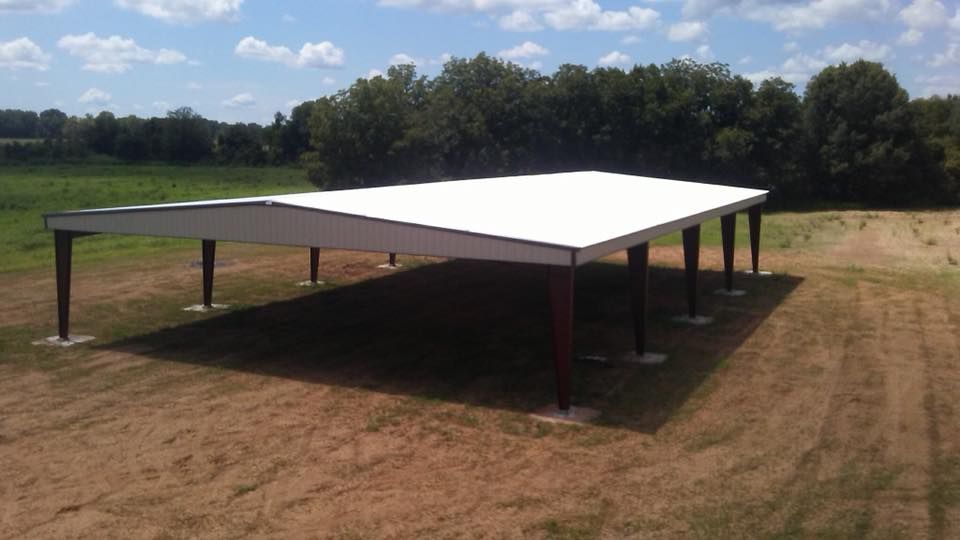 A large white building is sitting in the middle of a field.