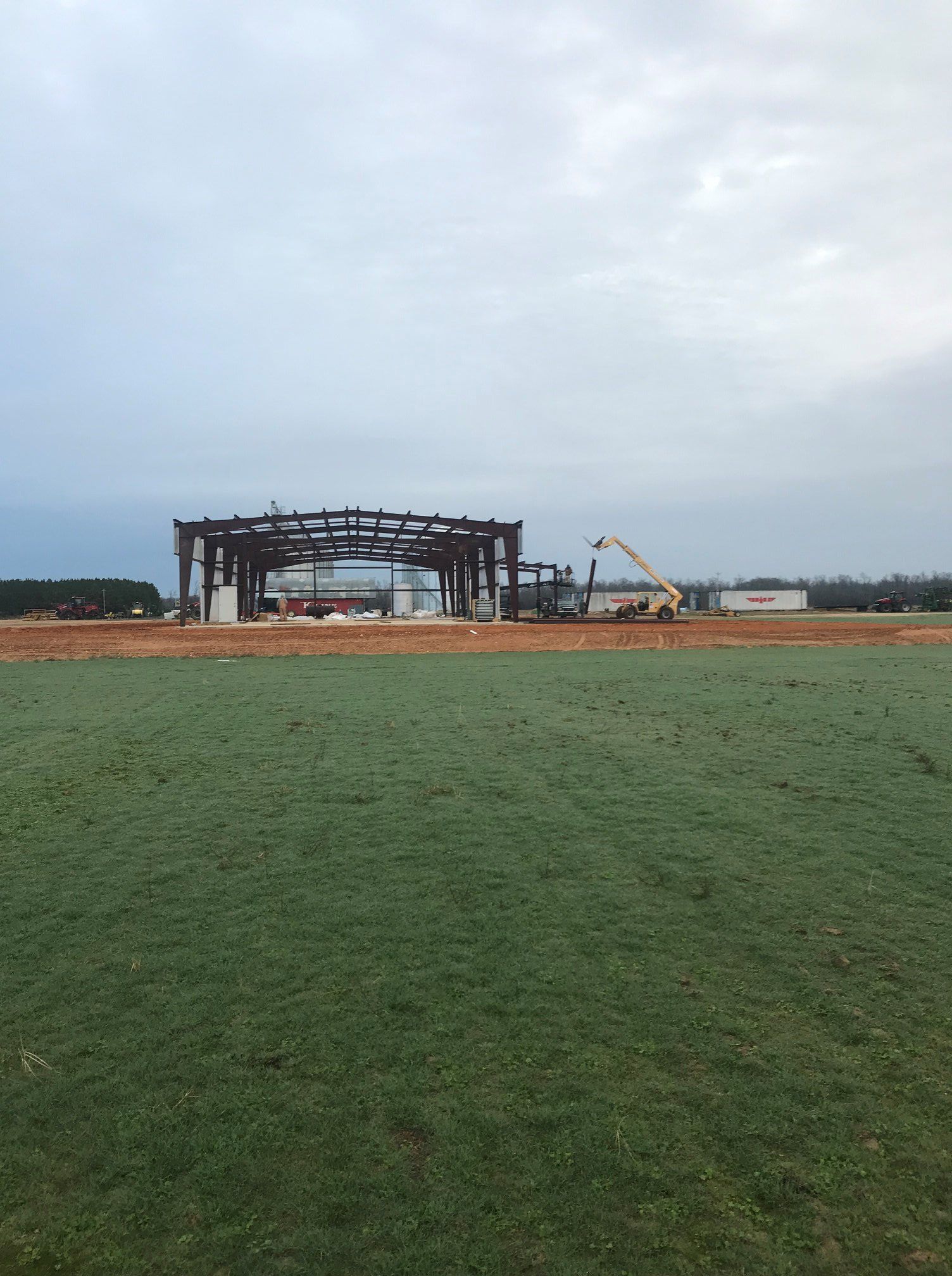 A large building is being built in the middle of a grassy field.