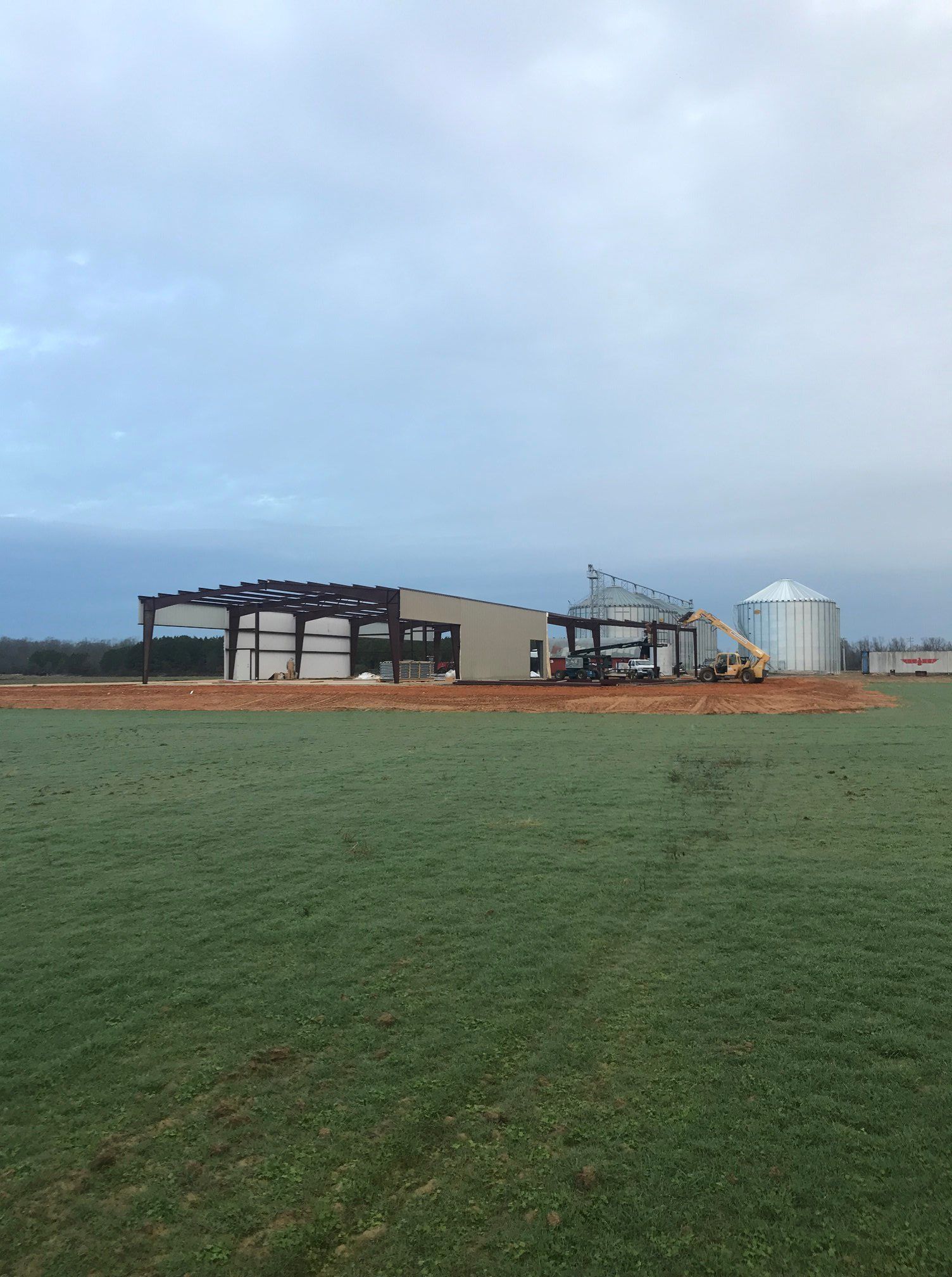 A large building is being built in the middle of a grassy field.