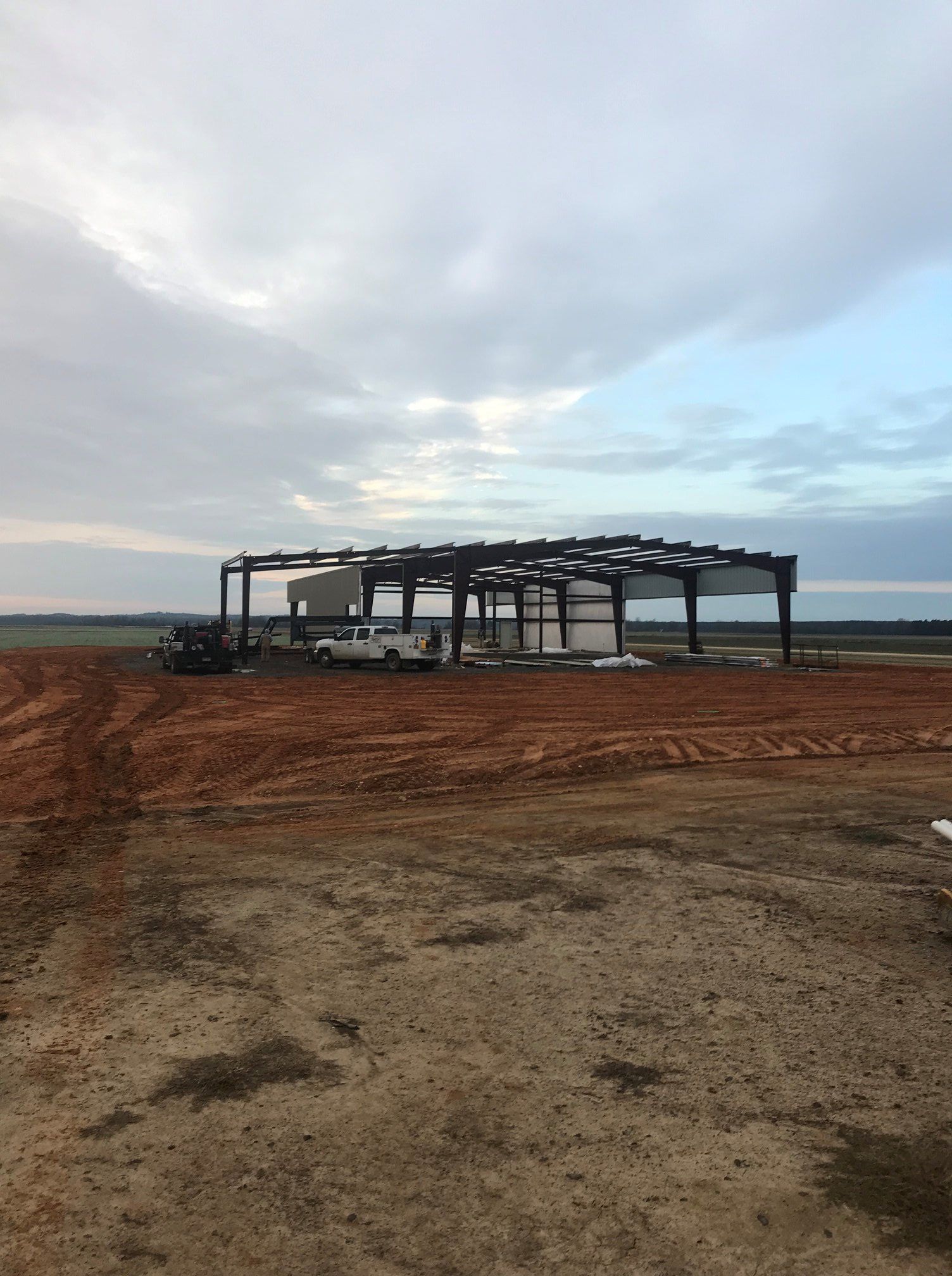 A large building is being built in the middle of a dirt field.