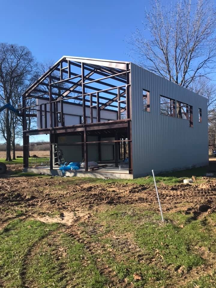 A large metal building is being built in a field.