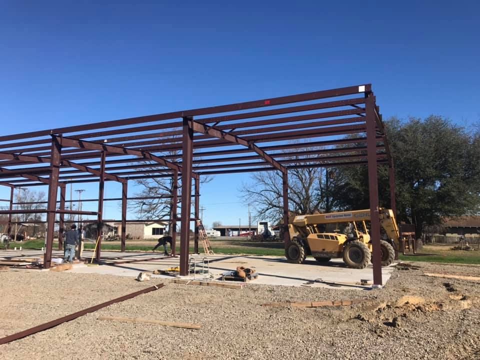 A large metal structure is being built with a bulldozer in the background.