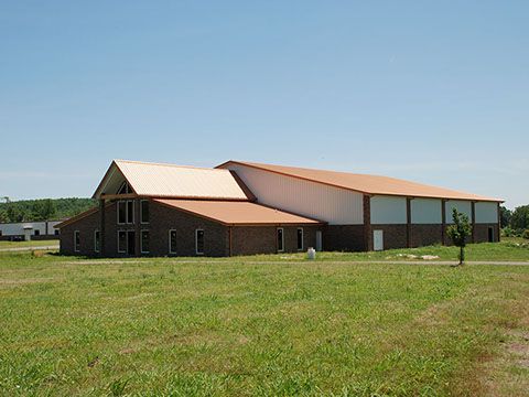 A large building with a brown roof is sitting in the middle of a grassy field.