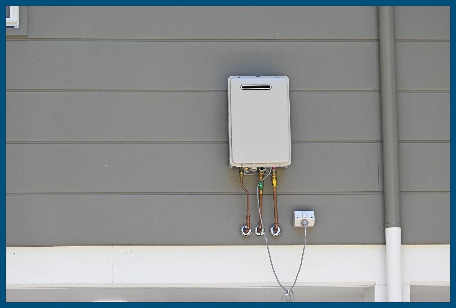 A white water heater is attached to the side of a house.