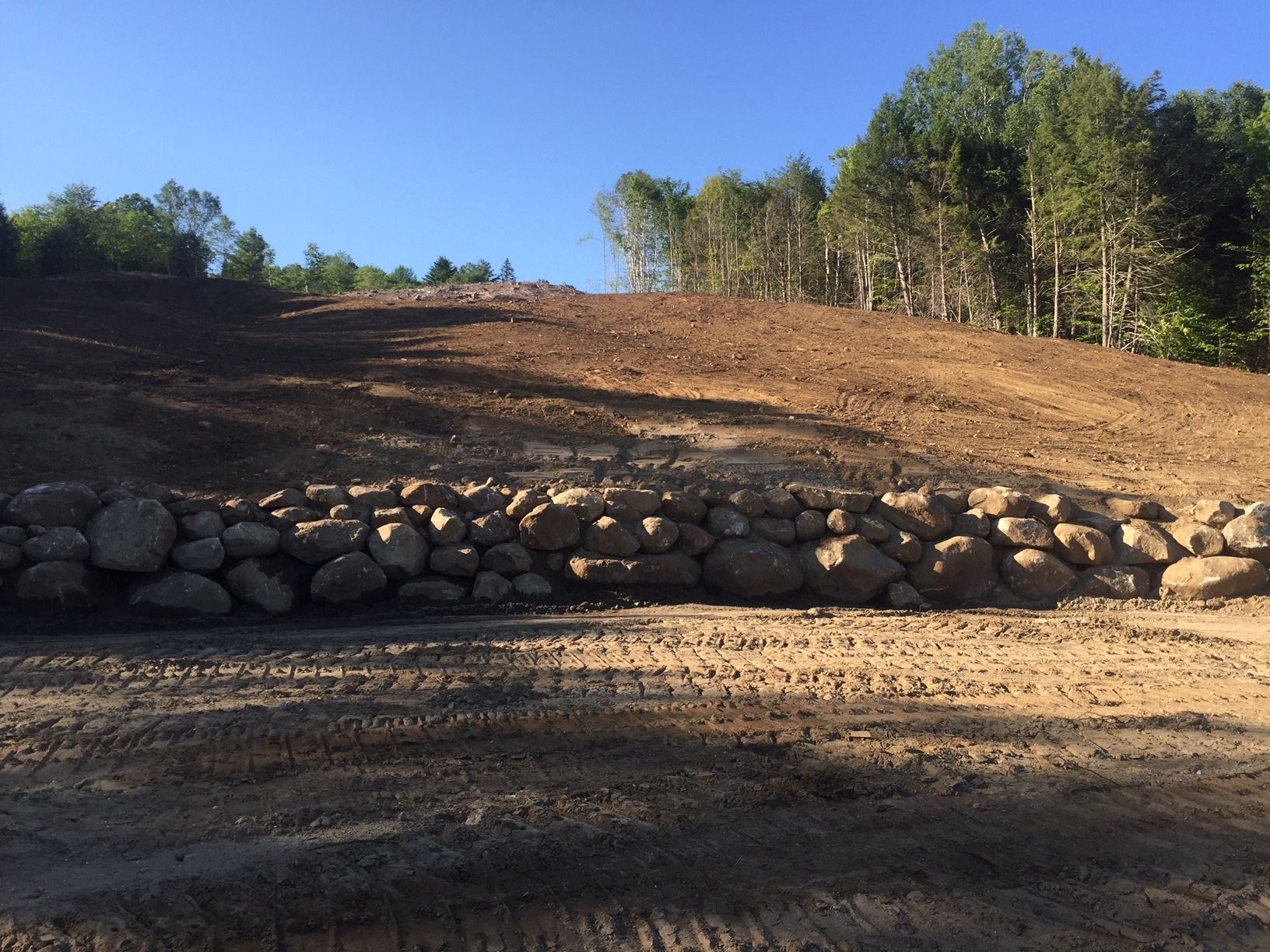 A dirt road going up a hill with trees in the background