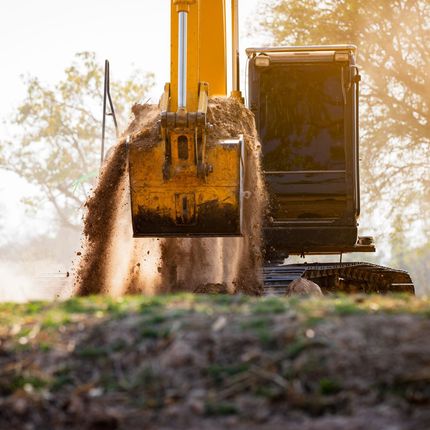 A dump truck is being loaded with rocks by an excavator